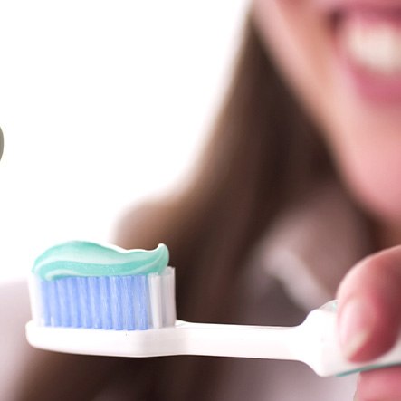 Lady applies toothpaste to brush