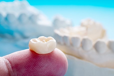 A close-up of a dental crown on a finger