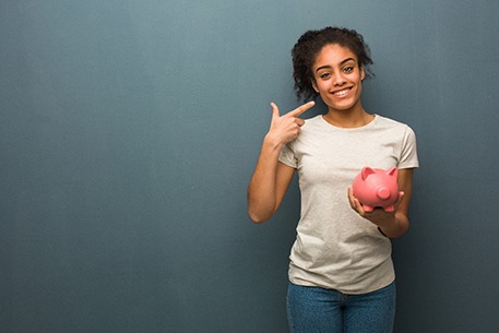 Woman holding a piggy bank and pointing at her smile