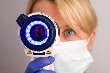 Dentist using advanced technology to perform an oral cancer screening