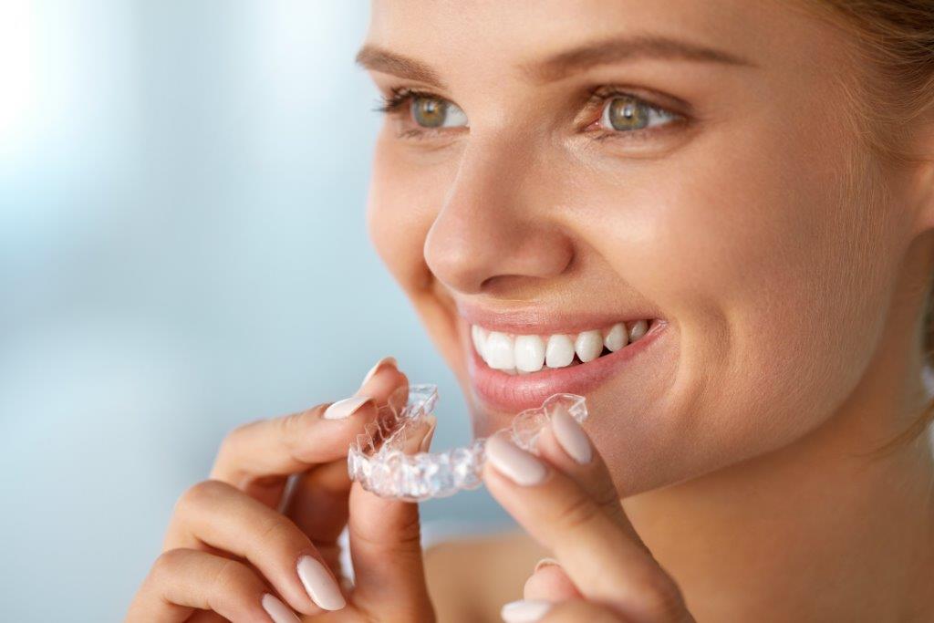 Woman placing an Invisalign tray during cosmetic dentistry treatment