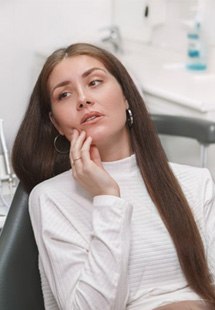 a woman holding her jaw due to tooth pain