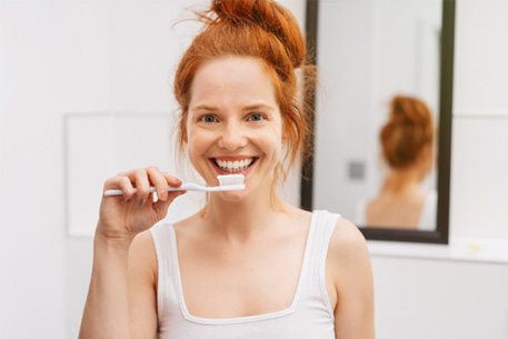 young woman brushing teeth in bathroom