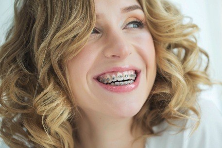Young smiling woman with traditional orthodontics