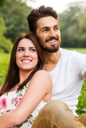 Couple smiling in a park after cosmetic dentistry