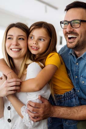 A couple and their daughter smiling together during family dentistry visit