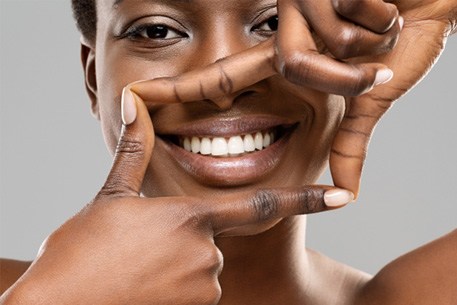 Woman framing her smile with her fingers