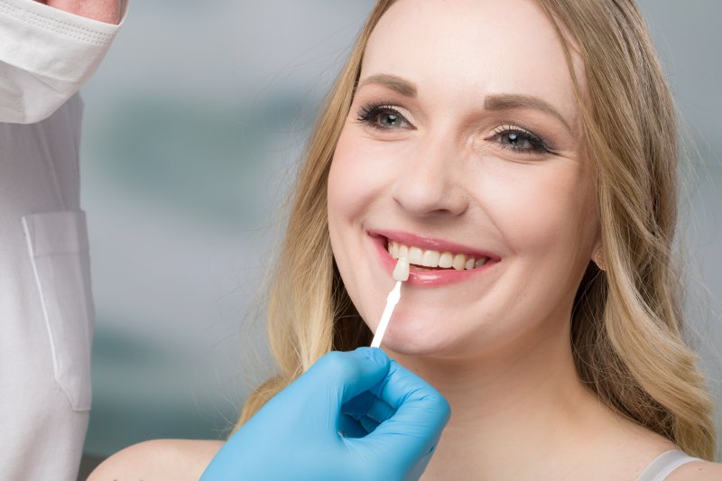 Cosmetic dentist helping patient with replacing veneers