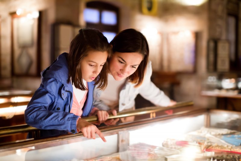 Mother and child looking at history of dental crowns exhibit