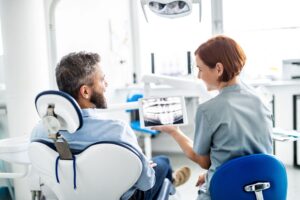 Dentist with short red hair discussing X-ray with patient