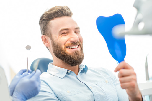 patient smiling while looking in dental mirror 