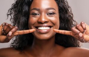 Woman smiling and pointing at her white teeth