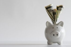 Cash stuffed into white piggy bank.